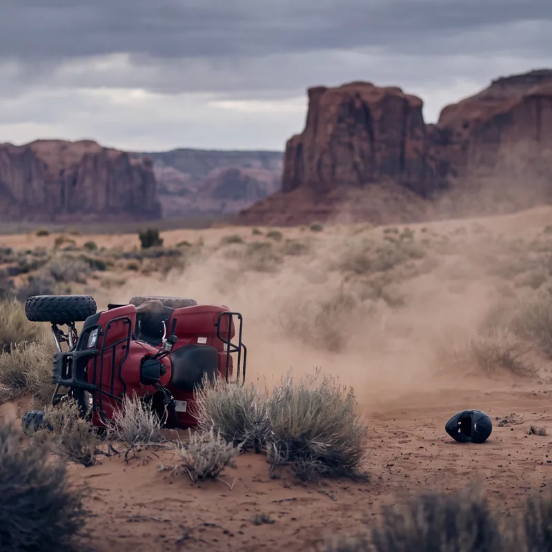 Overturned crimson ATV on a desert trail with Utah red rock formations in the distance